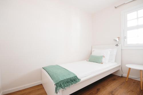 a white bed in a white room with a window at Apartamento Porta14 1 in Chaves