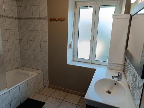 La salle de bains est pourvue d'un lavabo, d'une baignoire et d'une fenêtre. dans l'établissement Centre ville jardin privatif, à Morteau