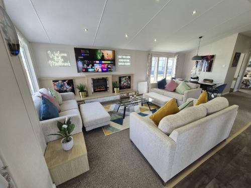 a living room with couches and a flat screen tv at The Retreat 2 bedroom lodge with sauna! in Walton-on-the-Naze