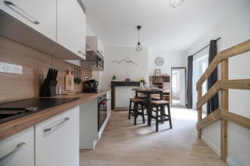 une cuisine avec des armoires blanches et une table avec des chaises dans l'établissement L'Evasion Urbaine #Hypercentre#Confort, à Clermont-Ferrand