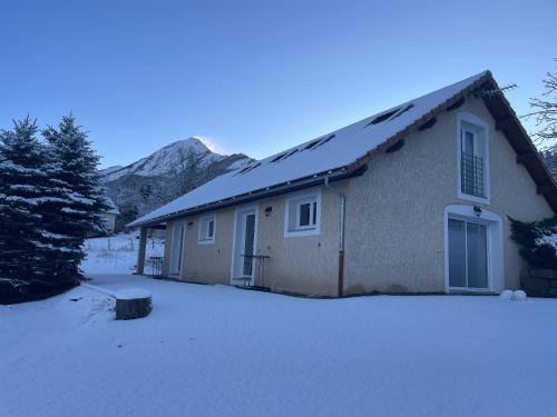 a house in the snow with a mountain in the background at Gîtes Belle Vue in Saint-Léger-les-Mélèzes