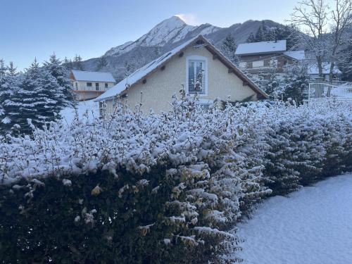 a house with a field of flowers in the snow at Gîtes Belle Vue in Saint-Léger-les-Mélèzes