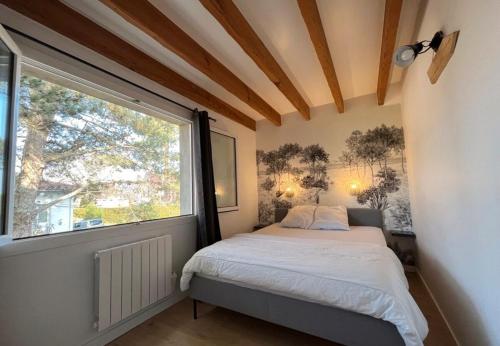 une chambre avec un lit et une grande fenêtre dans l'établissement Appartement Arcachon St Ferdinand, à Arcachon