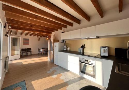 une grande cuisine avec des placards blancs et un salon dans l'établissement Appartement Arcachon St Ferdinand, à Arcachon