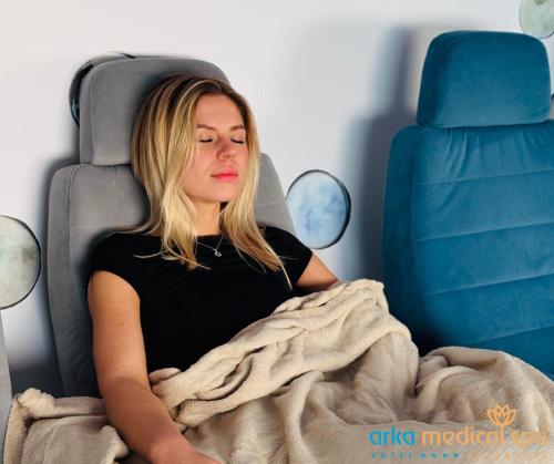 a woman sitting in a chair under a blanket at Arka Medical Spa in Kołobrzeg