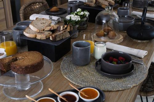 einen Tisch voller Essen mit Brot und anderen Lebensmitteln in der Unterkunft Home Emoi in La Gouesnière