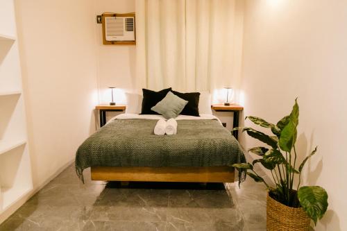 a bedroom with a bed with two tables and a plant at Casa Malia Siargao in General Luna