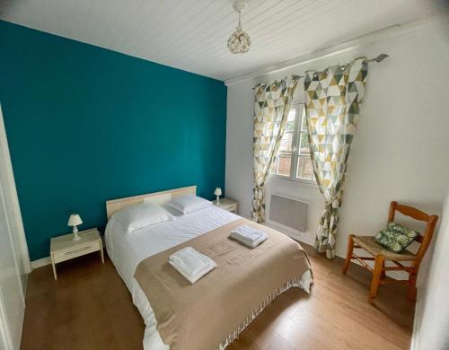 une chambre avec un grand lit et un mur bleu dans l'établissement Maison du sentier du littoral, à Gujan-Mestras