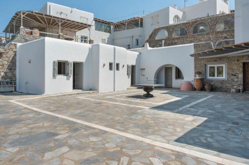 a courtyard with white buildings and a stone floor at Villa Coventina - Edge Suite in Agios Ioannis Mykonos