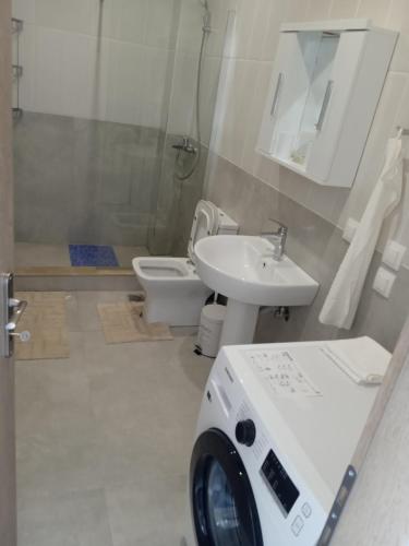 ein Badezimmer mit Waschbecken, Toilette und Waschmaschine in der Unterkunft Plomari View Stone Apartments in Plomari
