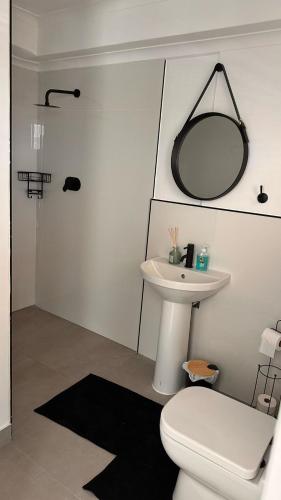 a bathroom with a toilet and a sink and a mirror at Coral Vistas Self Catering Apartments in Gordonʼs Bay