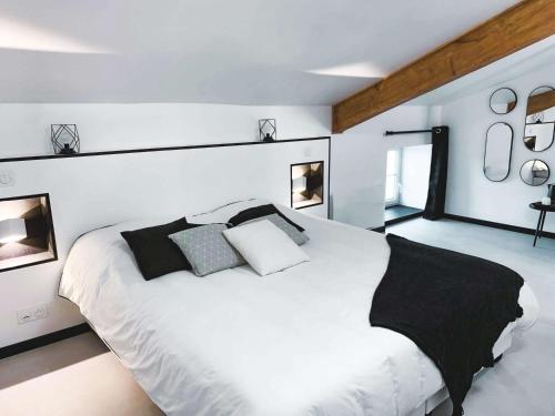 a bedroom with a large white bed with black pillows at Le Logis de la Gabirotte in Nieulle-sur-Seudre
