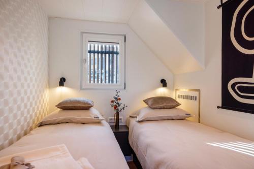 two beds in a room with a window at Holland Houseboat Lemmer in Lemmer
