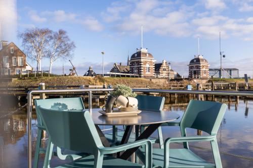 a table and chairs with water and buildings in the background at Holland Houseboat Lemmer in Lemmer