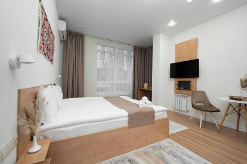 a bedroom with a bed and a desk and a tv at Q Apartment in Almaty