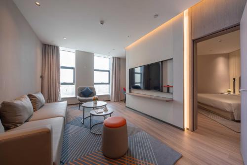 a living room with a couch and a bed and a television at Holiday Inn Express Turpan, an IHG Hotel in Turfan