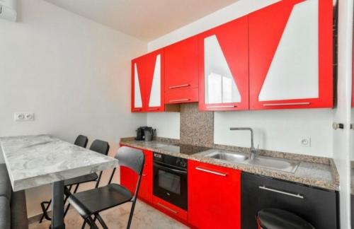 une cuisine avec des placards rouges et une table avec des chaises dans l'établissement Nice Libération beautiful 3 rooms- AC Wifi, à Nice