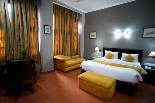 a hotel room with a large bed and a chair at The Corus Hotel in New Delhi
