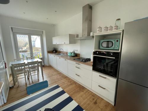 une cuisine avec des armoires blanches et un micro-ondes dans l'établissement La Marandière, à Saint-Quay-Portrieux