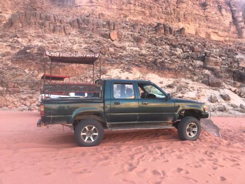 a green pick up truck parked in the desert at Wadi Rum Paris Cave in Wadi Rum