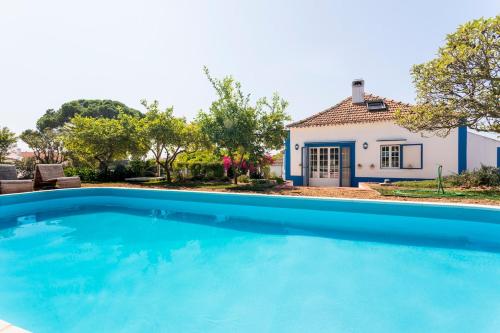 a large blue swimming pool in front of a house at Cottage with Pool,Gourmet BBQ,Wood Oven&Games Barn in Pontével