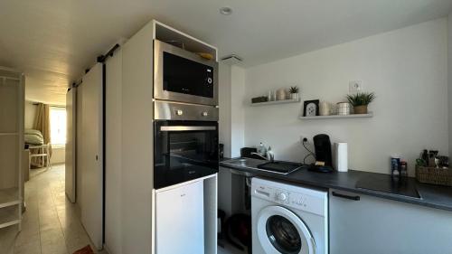 une cuisine avec un lave-linge et un micro-ondes dans l'établissement Le rivage secret, à Nevers