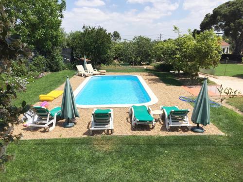a swimming pool with lawn chairs and umbrellas at Cottage with Pool,Gourmet BBQ,Wood Oven&Games Barn in Pontével