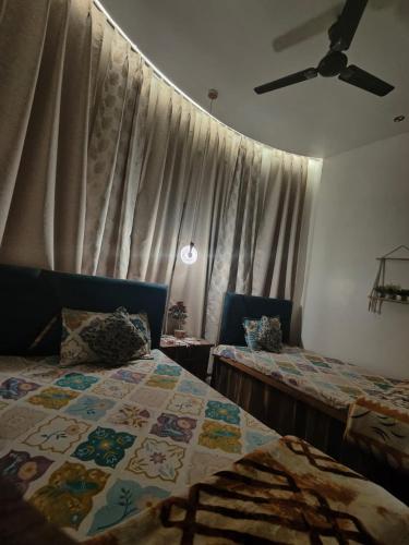 a bedroom with two beds and a window with curtains at Naari Hotel & Home Stay in Mathura