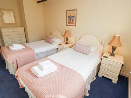a bedroom with two beds with pink and white sheets at Heatherview in Wooler