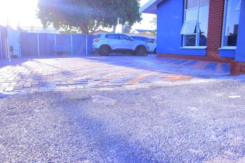 a white car parked next to a blue building at Kitty Guest House in Bellville