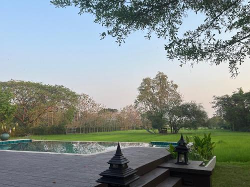 una terrazza in legno con piscina in un parco di The Puka Boutique Resort a Chiang Mai