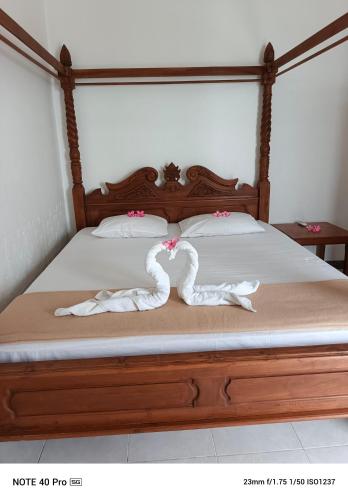 two swans towels are laying on a bed at Meninting garden house in Montongbuwoh
