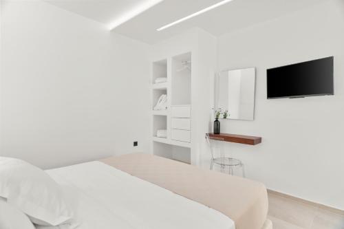 a white bedroom with a bed and a flat screen tv at Dream of Paros in Parikia