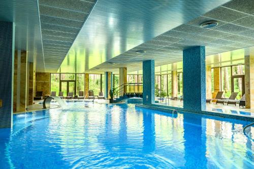 a large swimming pool with blue water in a building at SPA Hotel Infinity Park Velingrad in Velingrad