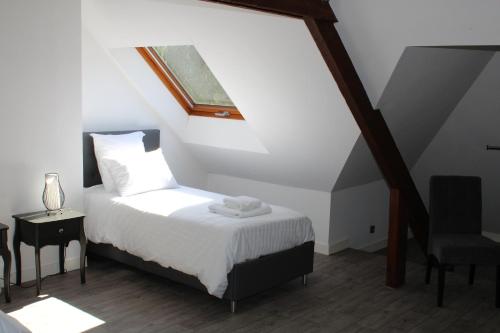 a bedroom with a bed with a window and a chair at Château de Lannouan in Landévant
