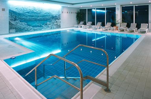 a large swimming pool with chairs in a building at Mercure Hotel Garmisch Partenkirchen in Garmisch-Partenkirchen
