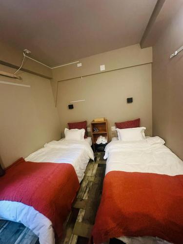 2 camas en una habitación con mantas rojas y blancas en e-hostel 心斎橋 403, en Osaka