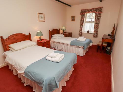 a bedroom with three beds and a window at Cherryburn Cottage in Wooler