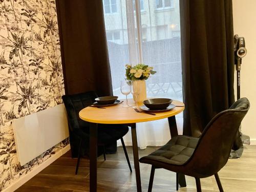une table avec deux chaises et un vase avec des fleurs dans l'établissement Escapade Détente avec Balnéo -043, à Rouen