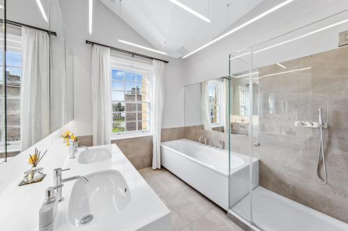 a bathroom with a tub and a sink and a shower at The Chelsea Villa in London