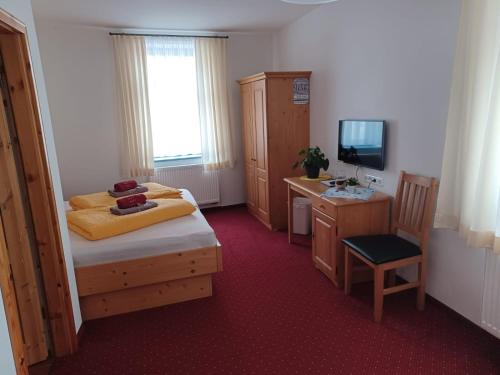 a bedroom with a bed and a desk and a television at Pension und Gaststätte "Zur Brauschänke" in Schöneck