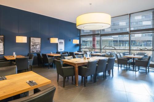 a dining room with wooden tables and chairs at Hotel Wolfsburg Centrum, Affiliated by Meliá in Wolfsburg