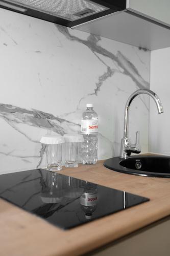 two bottles of water sitting on a counter next to a sink at Q Apartment in Almaty