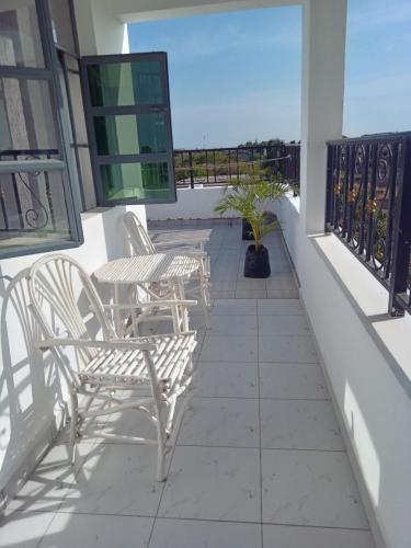a balcony with chairs and tables on a building at Eden Breeze Appartments in Diani Beach