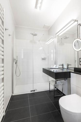 a bathroom with a shower and a toilet and a sink at Hotel Schloss Wilkinghege in Münster