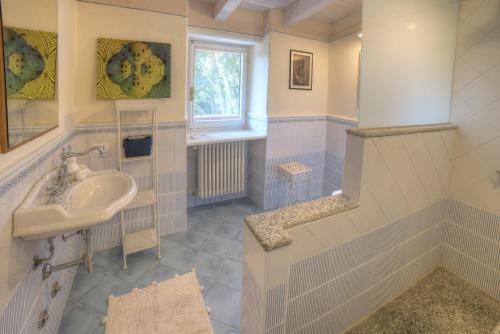 a white bathroom with a sink and a window at Villetta La Foresteria in Verbania