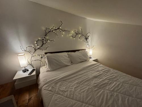 a bedroom with a white bed with two lamps at Casa del Cigno in Monterotondo