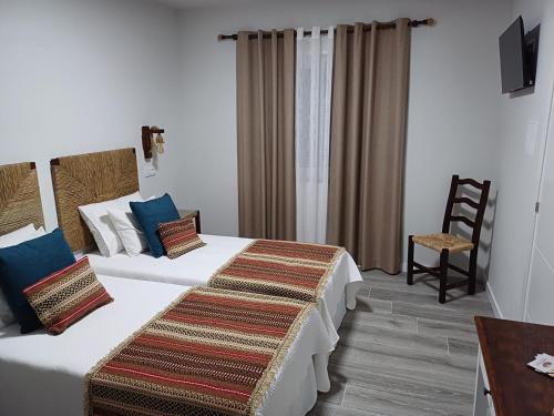 a hotel room with two beds and a chair at Casa da Vila in Campo Maior
