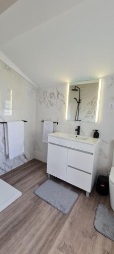 a white bathroom with a sink and a mirror at Casa Miramar in Algarvia