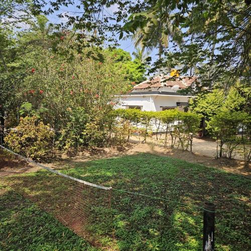 a yard with a fence in front of a house at Mysticgreens Home Stay in Piriyāpatna